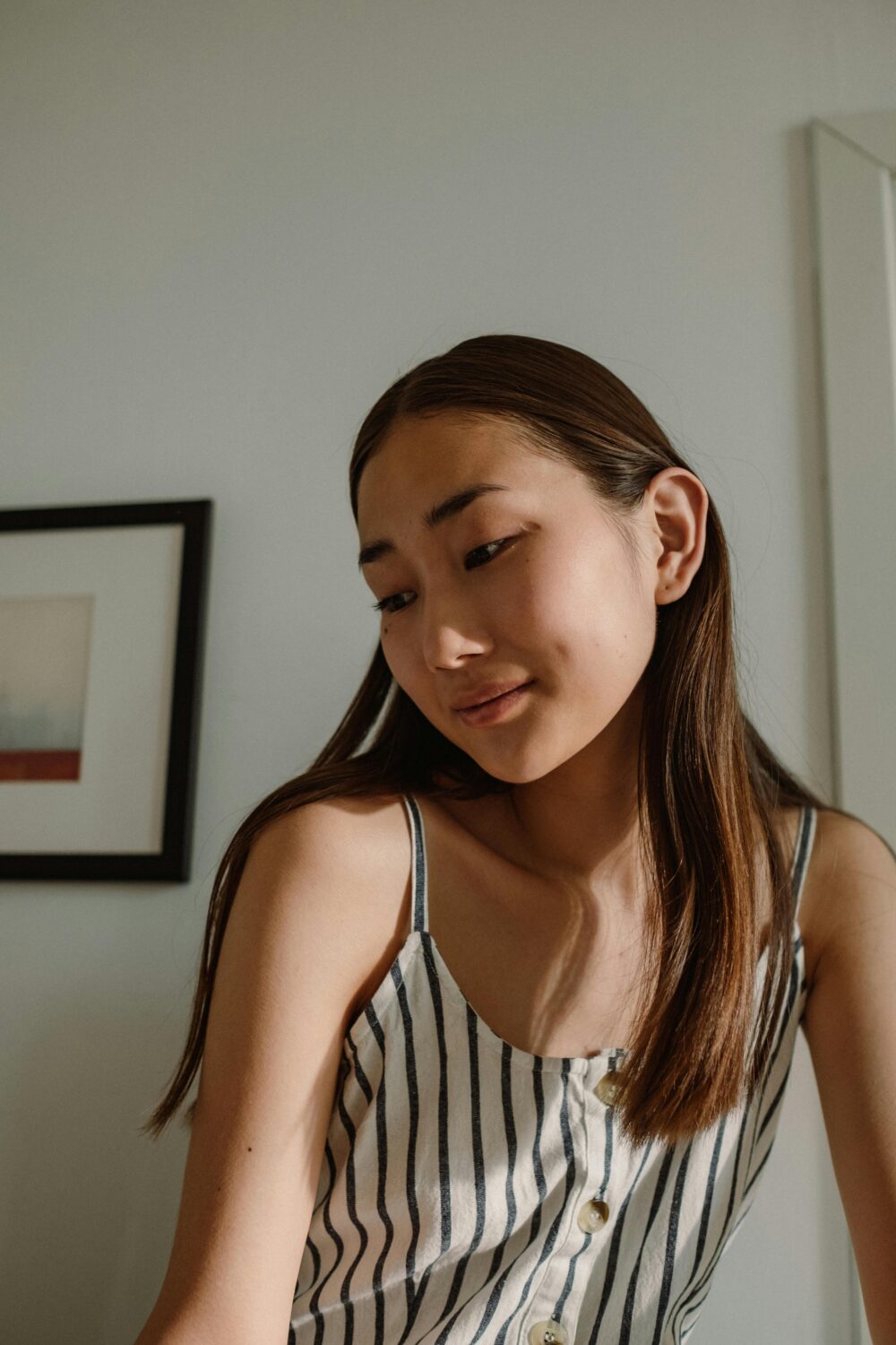 Person in striped top, soft lighting, framed art on wall.