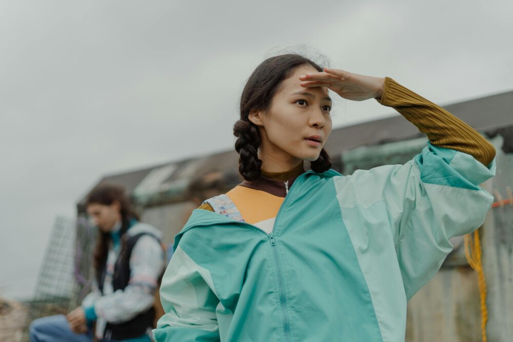 A person shields their eyes, looking into the distance.