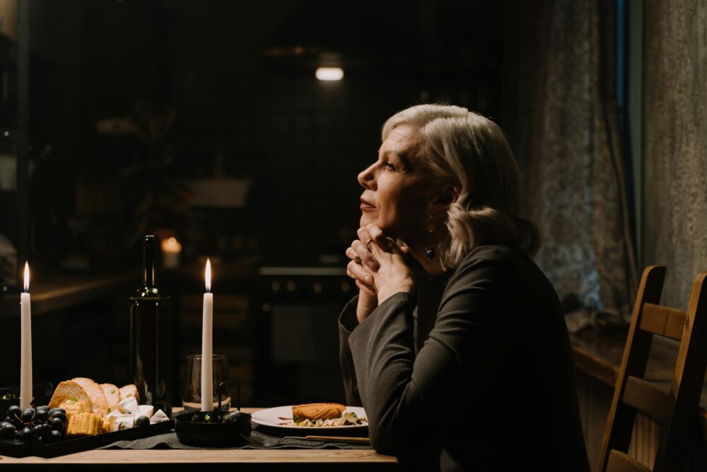 Person sitting at candlelit dinner table, appearing thoughtful and serene.