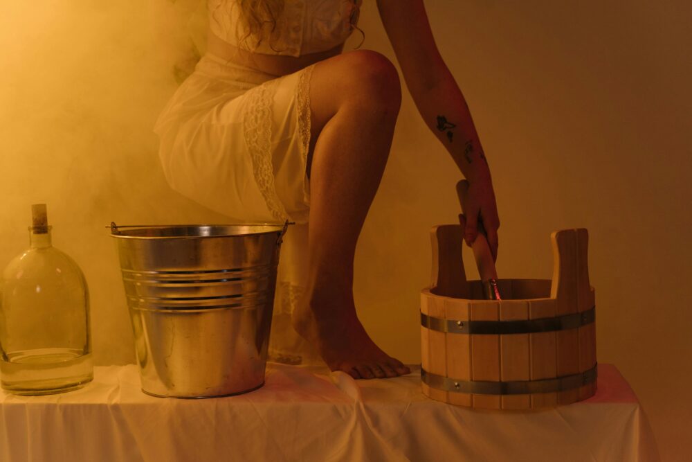 Person in white dress with buckets and bottle, yellow lighting.