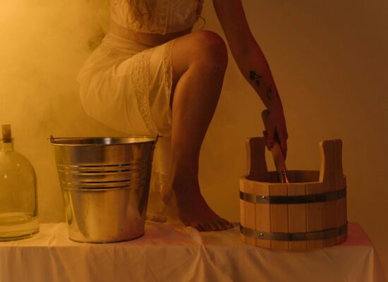 Person in white dress with buckets and bottle, yellow lighting.