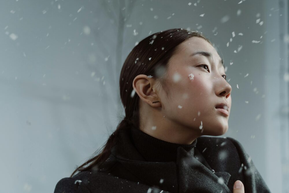 Person in winter coat with snowflakes falling around them.