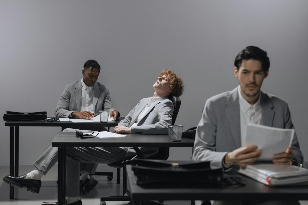 Three people in suits at desks in an office setting.