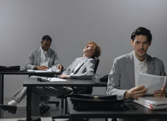 Three people in suits at desks in an office setting.