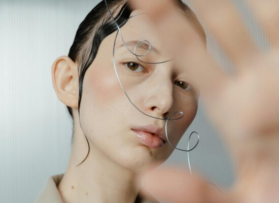 A person with wet hair and wire art on their face.