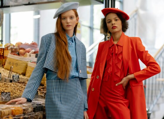 Two people in stylish outfits stand in a market stall.