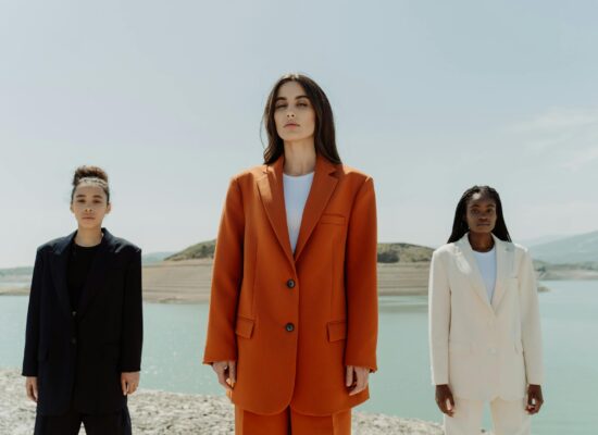 Three people in suits stand by a body of water.