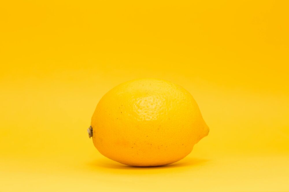 A single lemon on a bright yellow background, minimalistic style.
