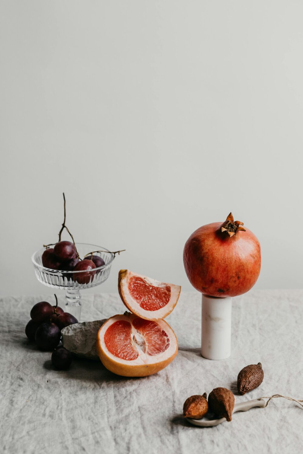 Assorted fruits including grapefruit, grapes, and pomegranate on table.