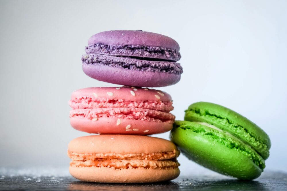 Four colorful macarons stacked on each other against white background.
