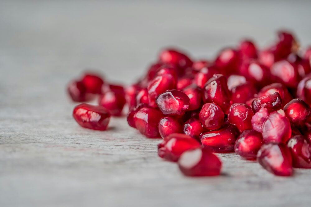 Close-up of fresh pomegranate seeds scattered on a surface.