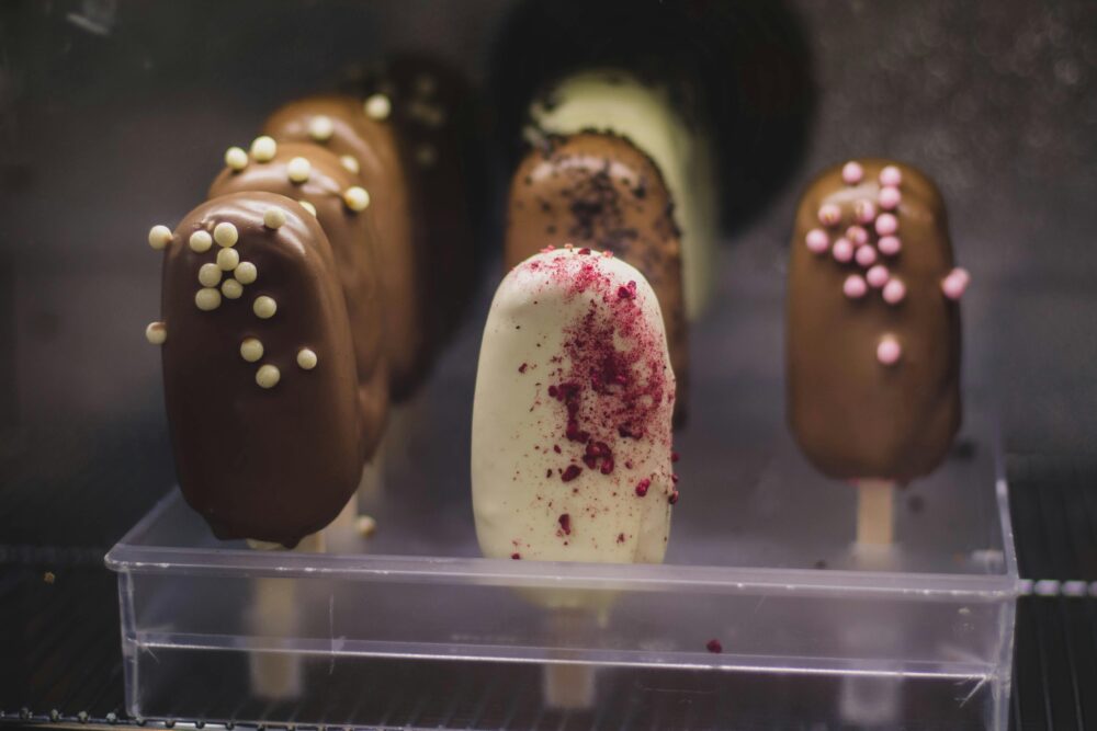 Assorted chocolate and vanilla ice cream bars with colorful toppings.
